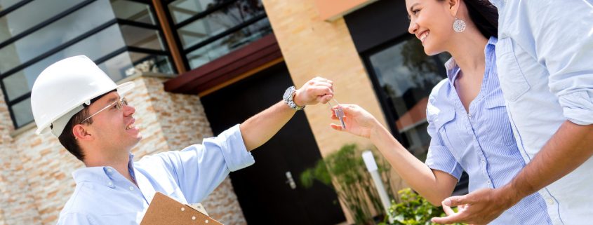 Architect handling keys of their new house to a couple